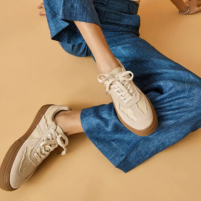 Person wearing blue jeans and beige sneakers on a beige background 