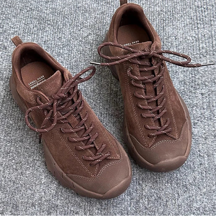 Pair of brown sneakers on a gray textured surface.