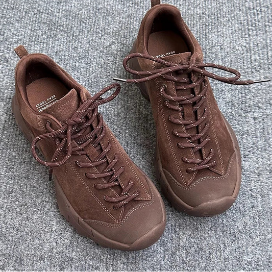 Pair of brown sneakers on a gray textured surface.
