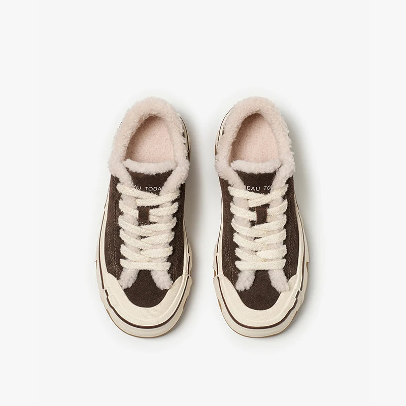 Pair of brown sneakers with white laces and fur-lined tops on a light gray background